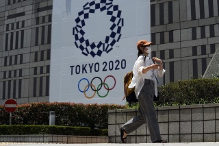 Žena kráča okolo bannera pre letné olympijské hry.