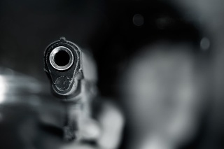 Black and white, woman pointing a old gun to front with one Hand on dark background