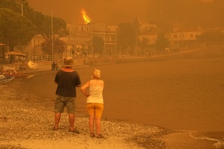 Horiace stromy pri pláži počas lesného požiaru v dedine Pefki na gréckom ostrove Evia.