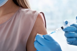 Male doctor holding syringe making covid 19 vaccination injection dose in shoulder of female patient wearing mask. Flu influenza vaccine clinical trials concept, corona virus treatment, close up view.