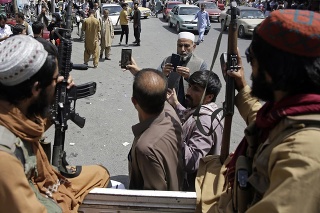 Afganci si fotia selfie s bojovníkmi Talibanu, ktorí hliadkujú na ulici v Kábule 19. augusta 2021.