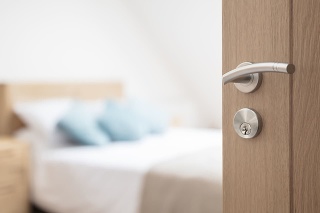 Hotel room or apartment doorway with key and keyring key fob in open door and bedroom in background