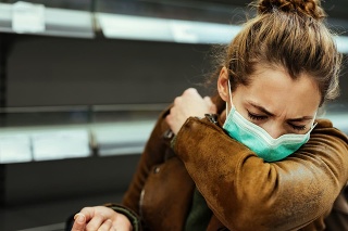 Sick woman buying in supermarket and coughing into elbow during COVID-19 pandemic.