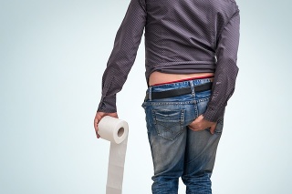 Man holding toilet paper roll and holding his butt on blue background. Diarrhea concept.