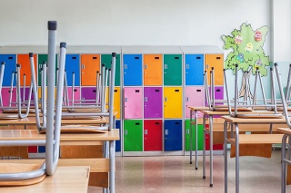 Modern emty classroom with colorful lockers and raised chairs on the tables