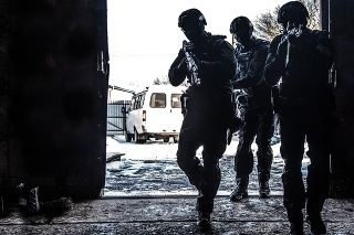 Silhouettes of police special operations forces tactical team, SWAT fighters aiming assault rifles while standing shoulder to shoulder in bright white doorway. Military tactical group storming room