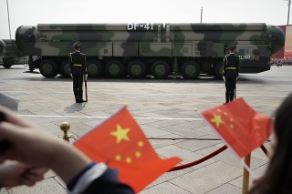 Diváci mávajú čínskymi vlajkami, keď sa vojenské vozidlá s balistickými raketami DF-41 pohybujú počas prehliadky na pripomenutie si 70. výročia založenia komunistickej Číny v Pekingu.