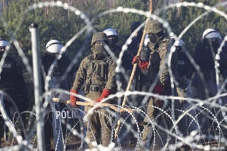 Poľskí policajti a príslušníci pohraničnej stráže hliadkujú pri plote s ostnatým drôtom, zatiaľčo migranti z Blízkeho východu a iných krajín, ktorí sa pokúšajú prekročiť hranice z Bieloruska do Poľska, sa zhromažďujú na hranici pri bieloruskej dedine Grodno