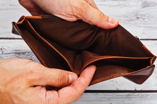 Person holding in hands totally empty leather wallet - crisis and poverty symbol