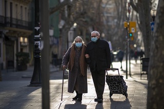 Starší pár kráča po ulici v Barcelone.