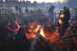 Migranti z Blízkeho východu a iných krajín, ktorí sa pokúšajú prekročiť hranice z Bieloruska do Poľska, sa zohrievajú pri ohni počas ich zhromaždenia na hranici pri bieloruskej dedine Grodno