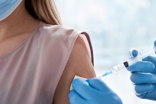 Male doctor holding syringe making covid 19 vaccination injection dose in shoulder of female patient wearing mask. Flu influenza vaccine clinical trials concept, corona virus treatment, close up view.