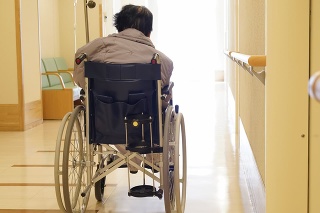 Back view of senior or elderly woman sitting on wheelchair in hospital hallway