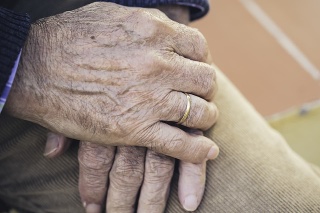 Elderly hand with ring resting on the other hand