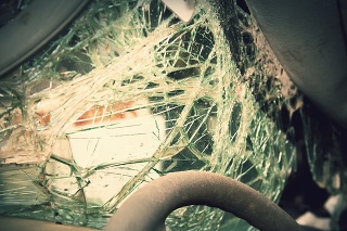 Close op of the steering wheel and shatterd windshield of a wrecked vehicle.  Cross processing.