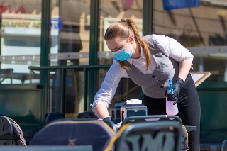 Vilnius, Lithuania - April 30 2020: Waitress with a mask disinfects the table of an outdoor bar, café or restaurant, reopen after quarantine restrictions