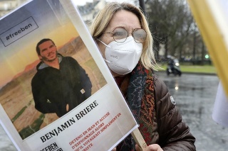 Žena drží transparent s fotkou Benjamina Briera.