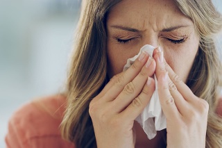 Shot of an attractive young woman feeling ill and blowing her nose with a tissue at home