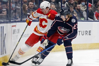 Na snímke zľava slovenský hokejista Adam Ružička z Calgary Flames a Adam Boqvist z Columbusu Blue Jackets bojujú o puk.