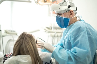 Senior dentist examining the teeth of a young woman