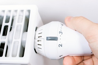 Male Hand Turns The Radiator Of A White Heater In The Living Room, Saving Energy Concept