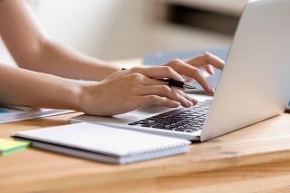 Cropped close up image woman hands holding pen typing on laptop student do homework prepare essay make research, businesswoman communicate online with client solve business questions distantly concept