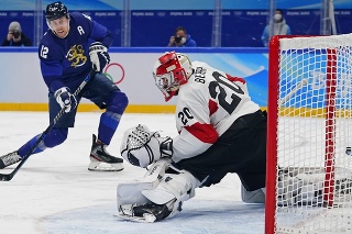 Fínsky hokejista Marko Anttila (12) strieľa gól švajiarskemu brankaŕovi Retovi Berrovi.
