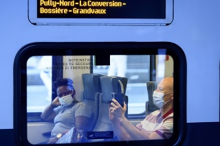 Ľudia s ochrannými rúškami na zabránenie šírenia nového koronavírusu sedia vo vlaku SBB CFF na železničnej stanici CFF v Lausanne.
