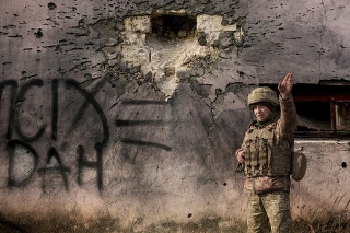 Un membre ukrainien des forces armées pointe du doigt la direction du bombardement à côté du bâtiment, qui a été touché par une grenade de mortier de gros calibre le samedi 19 février 2022 dans le village du front de Crimée dans la région de Lougansk, dans l'est de l'Ukraine.