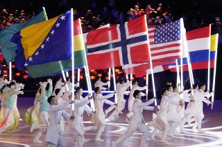 Účinkujúci nesú zástavy, tretia zľava je slovenská zástava počas záverečného ceremoniálu zimných olympijských hier ZOH 2022 v Pekingu.
