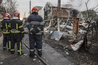 Hasiči sa pozerajú na vrak zostreleného lietadla v Kyjeve počas druhého dňa ruskej invázie na Ukrajine.