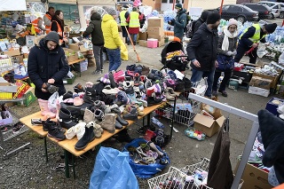 Utečenci z Ukrajiny si vyberajú oblečenie a obuv z humanitárnej pomoci na hraničnom priechode vo Vyšnom Nemeckom