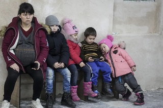Tehotná žena a deti sedia v ukrajinskom Mariupole na lavičke v improvizovanom bunkri v športovom centre, do ktorého sa zmestí až 2000 ľudí.