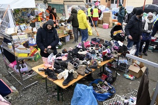 Utečenci z Ukrajiny si vyberajú oblečenie a obuv z humanitárnej pomoci na hraničnom priechode vo Vyšnom Nemeckom