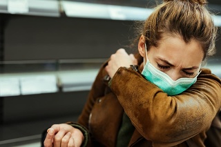 Sick woman buying in supermarket and coughing into elbow during COVID-19 pandemic.