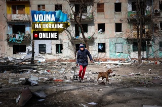 Muž sa prechádza so psom pri bytovom dome poškodenom ostreľovaním z bojov na predmestí Mariupolu.