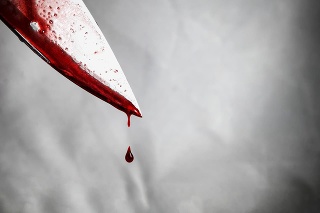 close-up of man holding knife smeared with blood and still dripping.