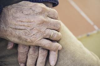 Elderly hand with ring resting on the other hand