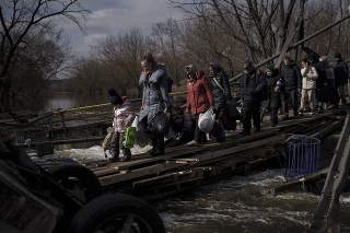 Ukrajinci pri úteku z Irpinu na predmestí Kyjeva prechádzajú popod zničený most.