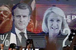 Na veľkoplošnej obrazovke sú fotografie súčasného prezidenta Emmanuela Macrona (uprostred) a líderky krajnej pravice Marine Le Penovej (vpravo) po zverejnení prvých odhadov 1. kola francúzskych prezidentských volieb