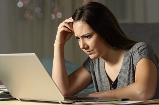Confused woman working online late hours in the night at home