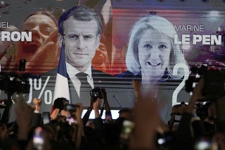Na veľkoplošnej obrazovke sú fotografie súčasného prezidenta Emmanuela Macrona (uprostred) a líderky krajnej pravice Marine Le Penovej (vpravo) po zverejnení prvých odhadov 1. kola francúzskych prezidentských volieb