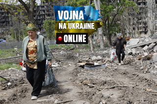 Ženy kráčajú okolo zničenej obytnej budovy v obliehanom prístavnom meste Mariupoľ.
