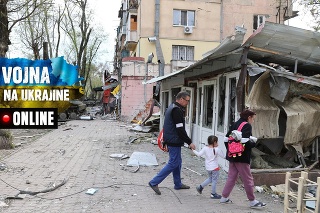 Žena, muž a dieťa kráčajú po zničenom Mariupoli.