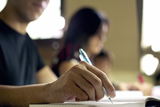 'Students doing homework and preparing exam at university, closeup of young man writing in college library'