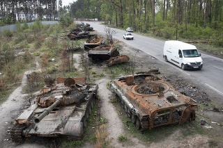 Vozidlá jazdia okolo zničených ruských tankov v dedine Dmytrivka pri Kyjeve.
