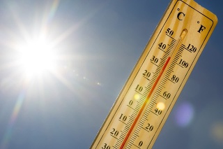 Mercury thermometer marking 39 degrees Celsius 100 Fahrenheit in a sunny day. Summer heat shown on mercury thermometer against the blue sky. Sunlight with sun flares.