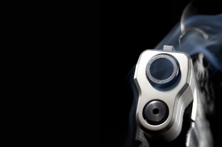3D rendering of a ghost gun with smoke rising from a handgun with a skull behind on a black background with copy space