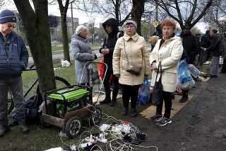 Miestni obyvatelia sa v piatok 22. apríla 2022 zhromažďujú pri generátore, aby nabili svoje mobilné zariadenia v oblasti kontrolovanej separatistickými silami podporovanými Ruskom v Mariupole na Ukrajine.