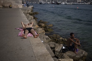Ľudia sa opaľujú na slnku počas horúčav v Marseille.